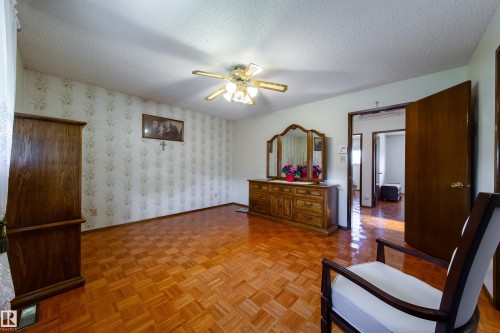 Spacious room featuring parquet wood-finish flooring, a textured ceiling, and a ceiling fan with integrated lighting - 8509 39B Avenue, Edmonton, AB - Indoor Photo Showing Other Room