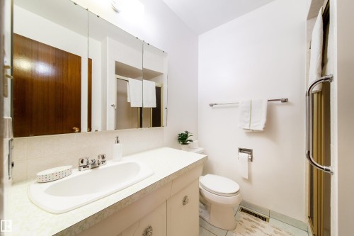 Bathroom featuring a vanity with integrated sink, chrome faucet, and expansive mirrored medicine cabinet - 8509 39B Avenue, Edmonton, AB - Indoor Photo Showing Bathroom