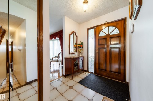 Entryway featuring a wood-panel door with decorative glass, frosted sidelight, and an arched transom window - 8509 39B Avenue, Edmonton, AB - Indoor Photo Showing Other Room
