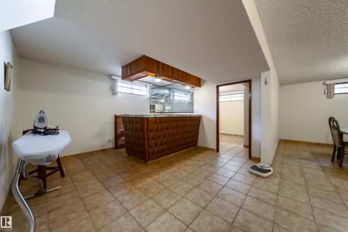 Entertainment room featuring a built-in bar with a stone countertop and tufted wood-finish paneling - 8509 39B Avenue, Edmonton, AB - Indoor