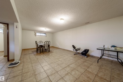 Spacious room featuring neutral tile flooring, white walls, and a textured ceiling - 8509 39B Avenue, Edmonton, AB - Indoor