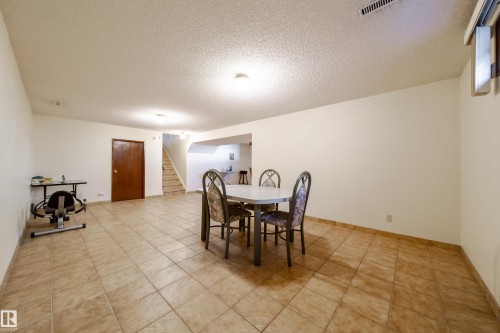 Spacious room featuring tile flooring, neutral wall tones, and a textured ceiling - 8509 39B Avenue, Edmonton, AB - Indoor