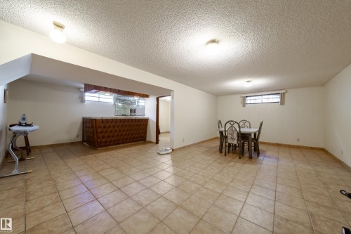 Spacious entertainment area featuring light-toned tile flooring throughout - 8509 39B Avenue, Edmonton, AB - Indoor