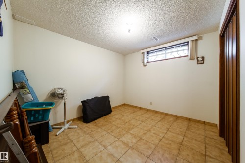 Cream-toned ceramic tile flooring, a window with security bars, and a wooden bifold door - 8509 39B Avenue, Edmonton, AB - Indoor Photo Showing Other Room