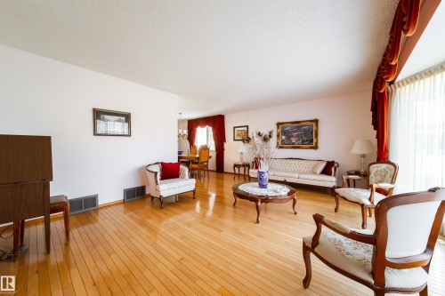 Expansive living space featuring wood-finish flooring, white wall tones, and recessed floor vents - 8509 39B Avenue, Edmonton, AB - Indoor Photo Showing Living Room