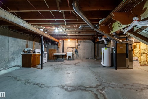 Unfinished basement featuring concrete walls and flooring, exposed ceiling joists, a utility sink, water heater, and furnace - 8509 39B Avenue, Edmonton, AB - Indoor Photo Showing Basement