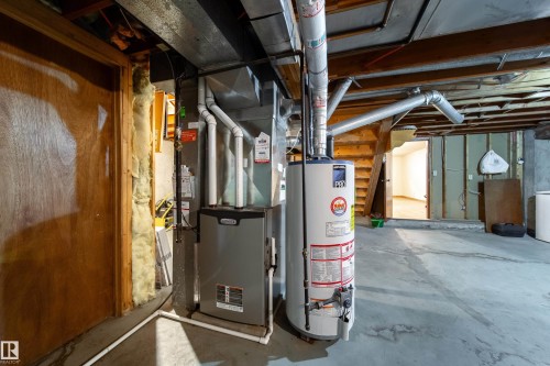 Utility room with concrete flooring, exposed ceiling joists, and a furnace with a hot water heater - 8509 39B Avenue, Edmonton, AB - Indoor Photo Showing Basement