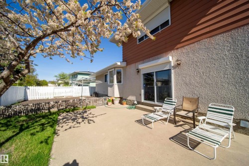 Expansive concrete patio with a sliding glass door entry to the property, featuring exterior sconce lighting and a bay window - 8509 39B Avenue, Edmonton, AB - Outdoor