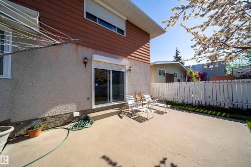 Concrete patio area featuring a white picket fence and mature tree - 8509 39B Avenue, Edmonton, AB - Outdoor With Exterior