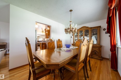 Dedicated dining area featuring wood-finish flooring, a built-in chandelier, and an open doorway to an additional room with wood-finish cabinetry - 8509 39B Avenue, Edmonton, AB - Indoor Photo Showing Dining Room