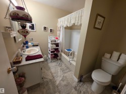 Main 4PC Bathroom on upper level featuring a vanity with an integrated sink, a built-in bathtub with shower, and linoleum flooring - 
