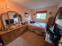 Bedroom featuring a window with a valance, light-toned walls, and ceiling with textured finish - 