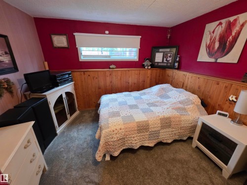 Red accent walls featuring a wood-paneled wainscoting - 25 Mcnabb Crescent, Stony Plain, AB - Indoor Photo Showing Bedroom