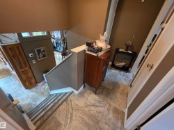 Multi-level interior featuring linoleum flooring at the landing, a painted staircase with white trim, and views into a lower room with wood-finish flooring - 