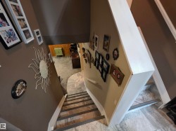 Staircase with tile-finish risers, a light-toned wood-finish handrail, and a neutral wall color - 