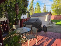Expansive outdoor deck featuring wood flooring and a glass-top table - 