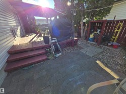 Outdoor deck with wood-finish flooring and three-step access to a stone paver patio - 