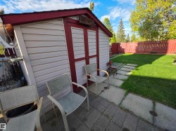 Detached storage shed with white siding and red trim - 
