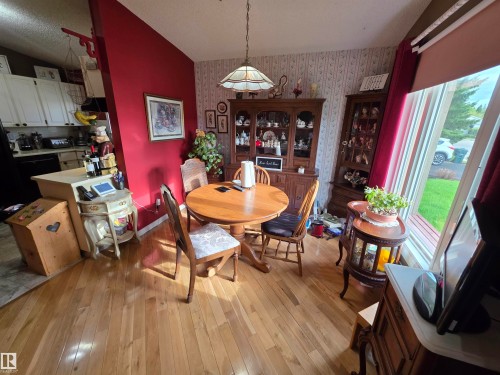 Hardwood-style flooring extends through this area with a prominent red accent wall - 25 Mcnabb Crescent, Stony Plain, AB - Indoor Photo Showing Dining Room