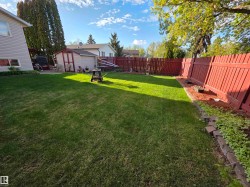 Expansive green lawn surrounded by a red wooden privacy fence - 