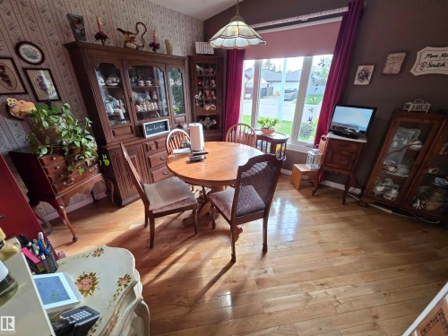 Dining area featuring wood-finish flooring, a decorative pendant light fixture, and a large window - 25 Mcnabb Crescent, Stony Plain, AB - Indoor Photo Showing Dining Room