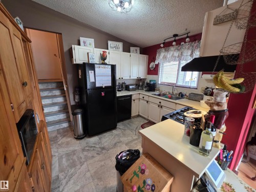Kitchen featuring white cabinetry, black appliances, light-toned countertops, and gas range - 25 Mcnabb Crescent, Stony Plain, AB - Indoor Photo Showing Kitchen With Double Sink