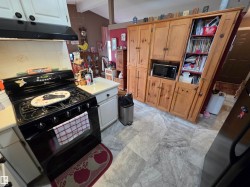 Kitchen featuring a black gas range, light-toned countertops, and substantial wood cabinetry - 