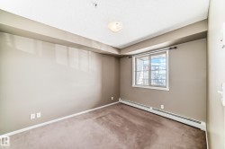 Carpeted room featuring neutral wall tones, a large window with white trim, and a ceiling-mounted light fixture - 