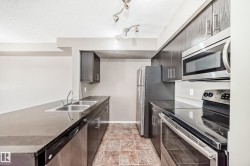 Kitchen featuring dark wood-finish cabinetry, stainless steel appliances, a double basin sink, and track lighting - 