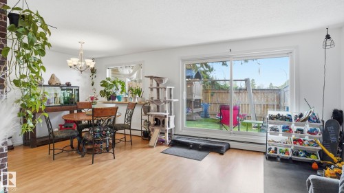 Light wood-finish flooring throughout, featuring a dining area with a chandelier - 105 5125 Riverbend Road, Edmonton, AB - Indoor