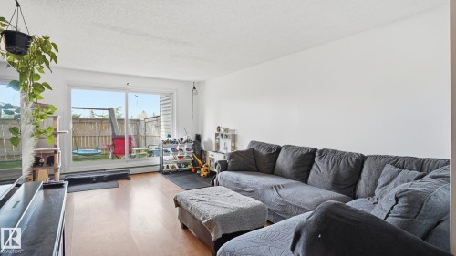 Sliding glass door opening to a private outdoor space with a wooden fence - 105 5125 Riverbend Road, Edmonton, AB - Indoor Photo Showing Living Room