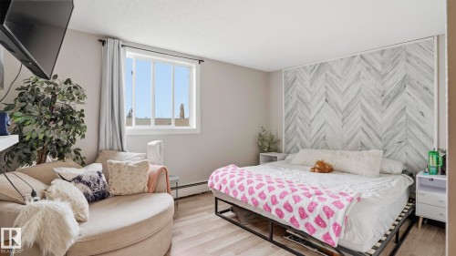 Interior room featuring light wood-finish flooring and a herringbone accent wall - 105 5125 Riverbend Road, Edmonton, AB - Indoor Photo Showing Bedroom