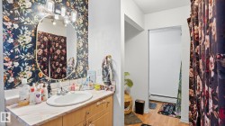 Bathroom vanity with light wood-finish cabinetry, a white oval sink, and a light-toned countertop - 