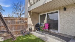 Ground-level patio featuring a sliding glass door, textured stucco exterior, privacy fencing, and a balcony above - 