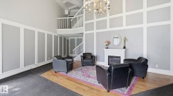 Two-story foyer featuring a grand chandelier, fireplace with white mantle, and decorative wall paneling - 