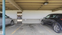 Covered parking structure featuring concrete flooring, exposed wood beam ceiling, and overhead lighting - 