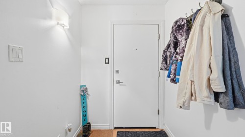 Entryway featuring a solid white door, wood-finish flooring, and white painted walls - 105 5125 Riverbend Road, Edmonton, AB - Indoor With Storage