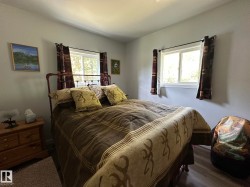 Bedroom featuring neutral wall color, two windows with white frames, and wood-finish flooring - 