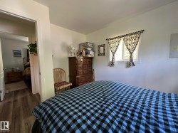 Bedroom featuring a window with natural light, wood-finish flooring, and a doorway opening to another room - 