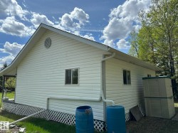 White siding exterior with a pitched roofline, round gable vent, and white lattice skirting - 