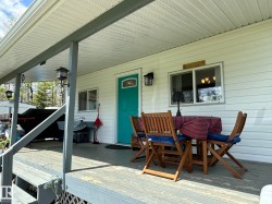 Front porch featuring a bright teal entry door, white horizontal siding, and a textured white soffit ceiling - 