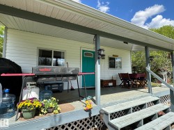 Front porch featuring white siding, a vibrant turquoise entry door, and a covered patio area - 