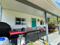 Covered porch featuring white siding, a teal entry door with decorative glass, and a wood-finish floor - 