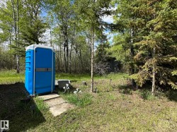 Grounds featuring a blue portable structure with a white roof and trim, surrounded by mature trees and natural landscaping - 