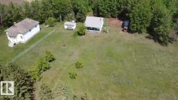 Expansive property featuring two structures, a detached shed, mature trees, and a large grassy area - 