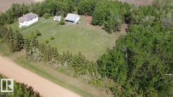 Expansive rural property featuring two residential structures, a large grassy area, and mature perimeter trees - 