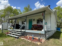 Exterior featuring horizontal white siding, a covered porch, and a teal entry door - 