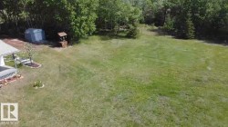 Expansive outdoor space featuring a large grassy area, mature trees, and a utility shed - 