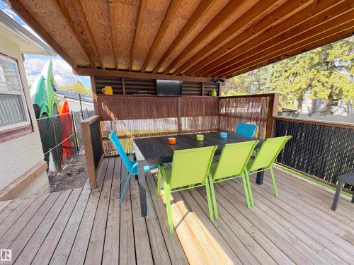 Expansive outdoor deck featuring wood-finish flooring, a covered patio area with a wood ceiling, and a built-in entertainment niche - 5510 Railway Avenue, Glendon, AB - Outdoor With Deck Patio Veranda With Exterior