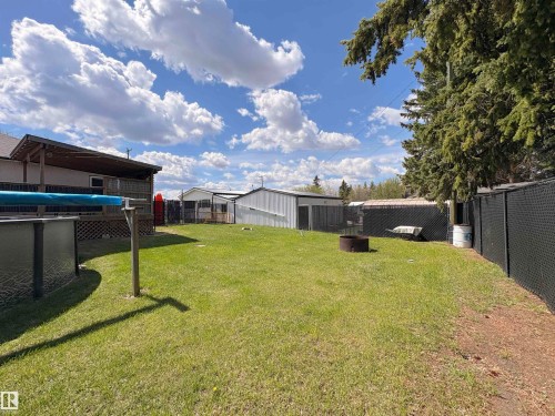 Spacious backyard featuring an above-ground pool, covered deck, and mature trees - 5510 Railway Avenue, Glendon, AB - Outdoor